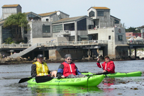 3 kayakers in front of Monterey Bay aquarium: 