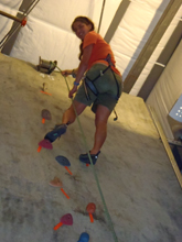 photot by Peter Ye Kelly Gomez at climbing gym: girl almost at the top of a route on a climbing wall