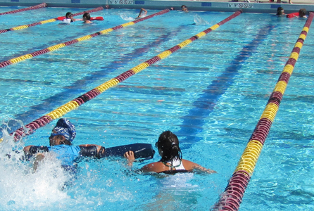 Wendy Tsang assists swimmer at Silicon Valley Kids Triathlon: lifeguard and swimmer in foreground, two other guards also assisting athletes in the background