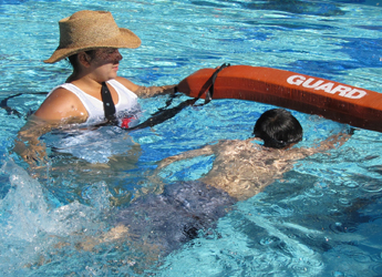 lifeguard Salina Martinez assists a swimmer at the Silicon Valley Kids triathlon: lifeguard wades with her rescue tube next to a distressed swimmer at a triathlon