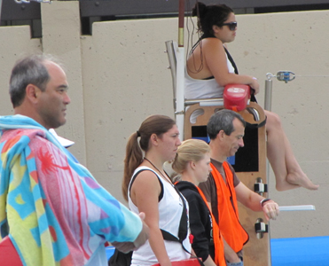 lifeguards and volunteers watch swimmers svkt 2011: lifeguards and volunteers watch swimmers, one lifeguard is wrapped in a towel after having just been in the water with a swimmer