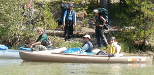 2011 paddlers and backpackers149 pixels: 2 backpackers on a trail by the lake and three kayakers in the water near them