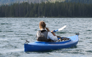 Alanna Klassen paddling against wind: girl in kayak with wind blown hair and whitecaps on water