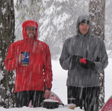 Eric and Alex breakfast 2011 winter trip: snow covered picnic table with stove, two guys holding mugs