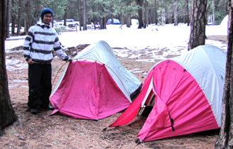 Jonathan with rain fly on upside down: guy stnading next to two tents of the same model, one with the rain fly on upside down