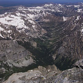 NPS photo N. Fork of Cascade Canyon as seen from the summit of the Grand Teton July 2010: tree covered canyon with snow capped mountains above