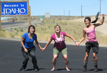 Phung, Kelly and Christina at Idaho border: three smiling grinning ladies with Idaho sign in background