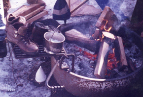 campfire with boots: campfire ring with boots and hat drying to the side and on the grate