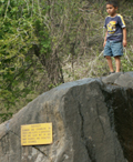 child climbing on rock with warning sign about not climbing on the rocks: 