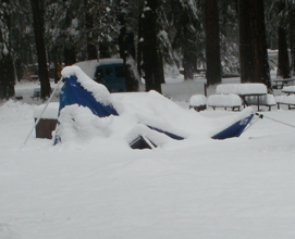 collapsed dining canopy at neighbor's site: deep snow with part of a dining canopy and poles on the ground showing through