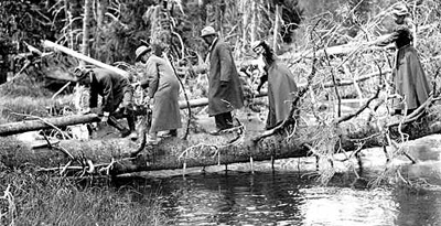 hikers crossing creek by EB Thompson NPS Historic Photograph Collection: hikers in long coats circa 1920s crossing creek on a fallen tree by EB Thompson NPS Historic Photograph Collection