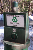 propane canister recycling only: a large trash can with a propane canister on top of it and a sign that says propane canister recycling only