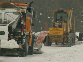 snowplows stay back: two snowplows, one with a sign that says stay back