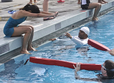 ted and kanishka help on diving day by Sumana Praharaju: two volunteers give advice to a student just before she tries a dive from a sitting position at the side of a pool