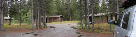 three cb cabins: three wood cabins and a road with big rain puddles