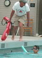 volunteertrilifeguardAlanAhlst.rand: lifeguard leaning towards swimmer supported by a noodle