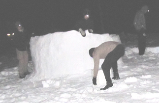 2010 building igloo at night: photo taken at night as campers build a round wall of snow five feet high, not quite finishing an igloo. Photo by Alan Ahlstrand
