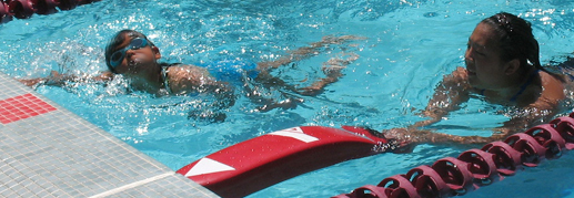 Joyce Kuo with swimmer at 2010 Kids tri: lifeguard with rescue tube swims next to small child photoshop smudge tool used to protect child's identity