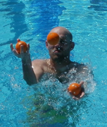 Mitchell Conley juggles while treading water: man juggles three balls while in a swimming pool