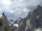 NPS photo adamteewinotgrand by Kfinch: a man sits on top of a peak, looking in the direction of other peaks in the Tetons
