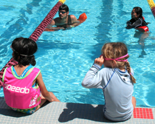 Paul Barron and Bernadette Milan at Kid's tri: two adult lifeguards in the pool with two young girls at pool edge just before a triathlon swim photo by Alan Ahlstrand, Red Cross Lifeguard Instructor and Volunteer of Record for De Anza College