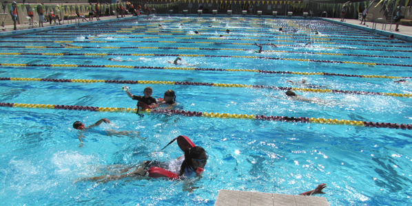 SCVKT 2012 two guards assisting swimmers: long view of pool with boy in near lane having trouble with his face mask and a lifeguard assisting him