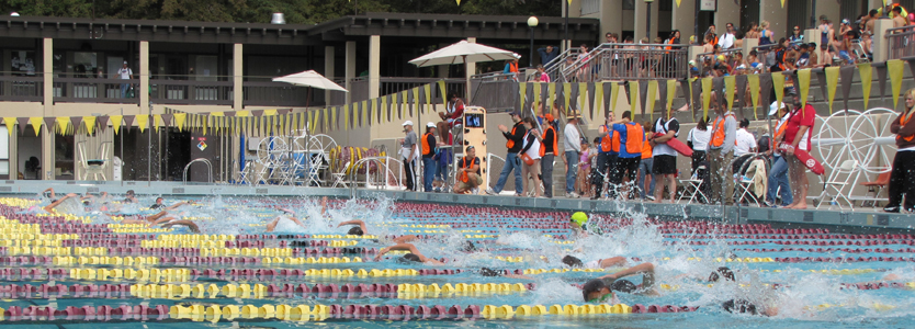 Silicon Valley Kids Triathlon 2011 start: one wave of swimmers in the pool, volunteers at pool edge and the next wave of swimmers waiting in the bleachers