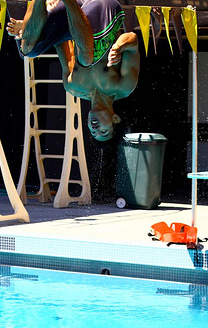 back flip photo by Joyce Kuo: swim student in mid air upside down during a back dive from a one meter diving board