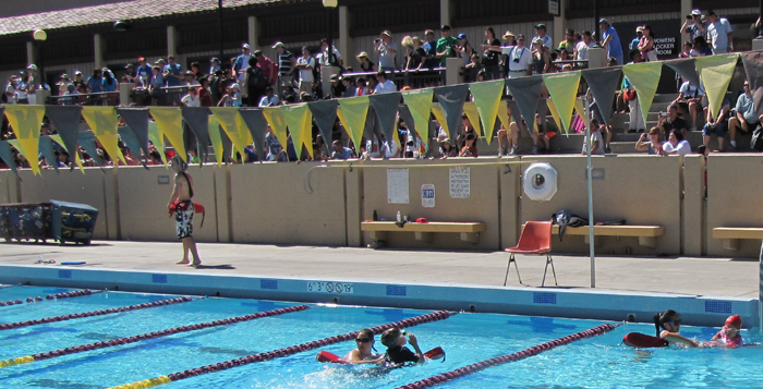 bleachers full of parents at kids triathlon: bleachers full of relatives and friends at kids triathlon, with two lifeguards in the water assiting swimmers