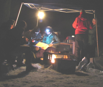 campfire songs winter 2010 300 pixels: nighttime shot of at least a foot of snow on the ground, a blazing campfire, guitarist seated at picnic table with other campers looking at songbooks and singing