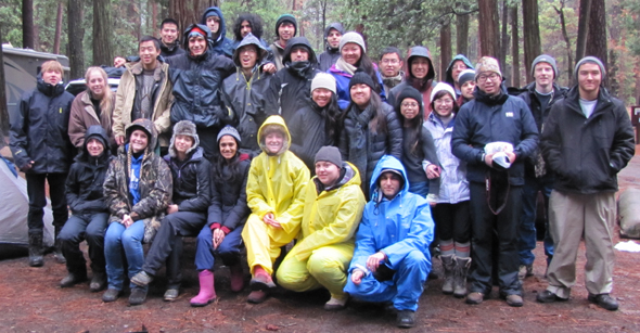 group photo Yosemite winter trip 2014: 30 people in rain gear sitting or standing on a picnic table in a Yosemite campsite