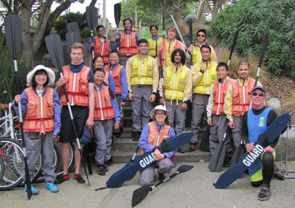 group photo on land kayak March 2014: people standing in rows on a wide staircase, wearing lifejackets and holding paddles and a couple of rescue tubes