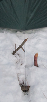 guylines anchored to branches in snow: a guyline shown from a tent to branches buried in snow