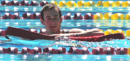 lifeguard Eric Champlin assists swimmer at Silicon Valley Kids triathlon: lifeguard swims with rescue tube alongside struggling swimmer