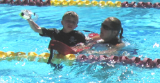 lifeguard assists distressed child with faulty face mask: lifeguard assists distressed child who has stopped swimming because his face mask was loose and/or filled with water