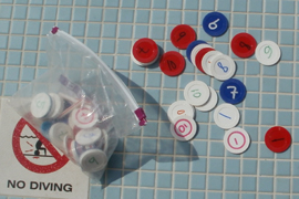 numbered poker chips: numbered poker chips sitting on a tiled pool deck