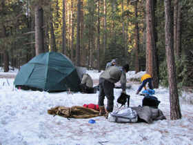 packing up 2010 winter trip: packing up camp on a winter trip, snow on ground, one tent almost packed up, another having it's guylines dug up where they were anchored to branches now frozen in the snow