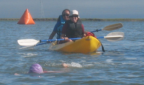 2009 senior games triathlon lifeguards April Sanchez and Susan Restani: 2009 Senior Games triathlon lifeguards April Sanchez and Susan Restani paddle a kayak near a swimmer with an orange turn bouy in the background