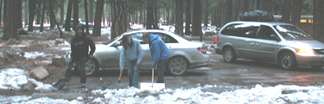 shoveling snow at campsite parking space: three people shoveling snow to clear a campsite parking space