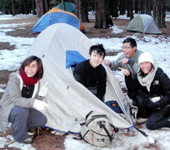 student who did not check his pack at bedtime: three campers pointing at another camper sitting at the opening to his tent