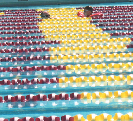 svkt swimmer needing assistance 2010: rows of pool lane lines with one adult lifeguard and one swimmer in need of a rescue tube to hold on to and kick photo by Alan Ahlstrand
