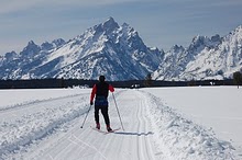 teton park road winter nps photo: cross country skier on snowy road with mountains in background