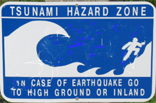 tsunami hazard zone sign 150 pixels: sign warning of a tsunami hazard zone with a drawing of a huge wave and a person climbing up a slope