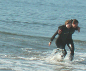 walking assist waterfront lifeguard practice: one lifeguard candidate assists another to walk out of the ocean