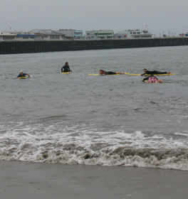 waterfront guard paddlers 2010: waves slightly breaking on shore and 5 waterfront lifeguard candidates on rescue boards out in the bay