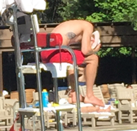 lifeguard sitting with his head in his lap and his rescue tube behind him as a backrest