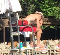 lifeguard sitting with his rescue tube behind him as a backrest