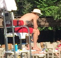 lifeguard sitting with his rescue tube behind him as a backrest