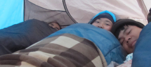 three people in sleeping bags in a tent