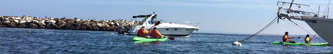 two tandem kayaks in foreground, large fishing boat behind